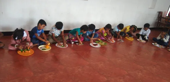 Creative artwork by 1st standard students at one of the best schools in Salem, depicting a lotus carved from an onion and curry leaves on a ceramic plate.