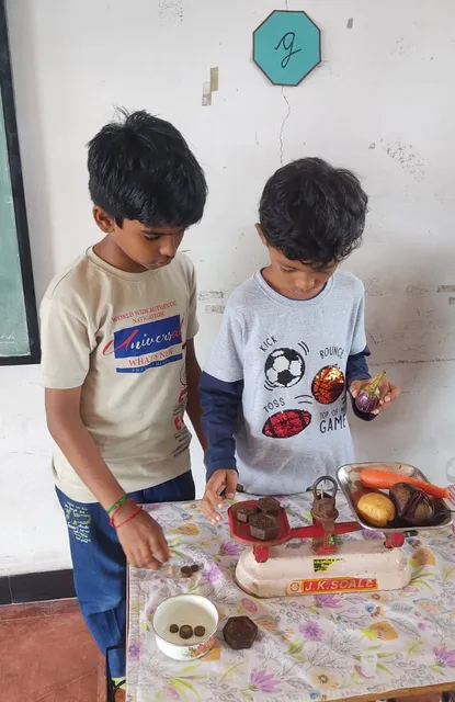 Grade 4 students learning to measure mass with traditional scales by weighing fruits and vegetables in a science class.