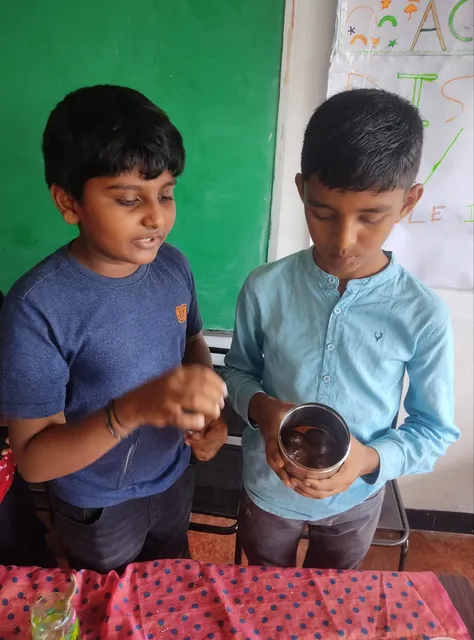 Fifth-grade students at Vidhya Peetham i-School engaging in a group science experiment, exploring solubility by mixing various substances in water, as part of their states of matter activity.