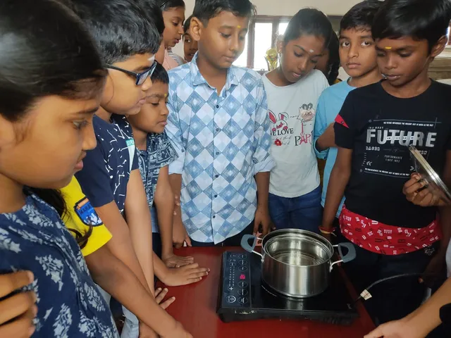 A group of 5th graders at Vidhya Peetham i-School watching water boil on an induction stove, studying evaporation and condensation processes for 5th grade states of matter activity.