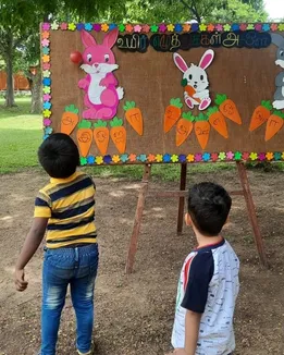 Colorful chart cutouts of rabbits and carrots used for Tamil alphabet learning at a CBSE school in Salem.
