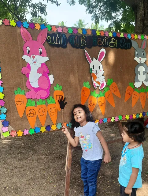 Young learner at a Salem CBSE school identifying 'உயிர் எழுத்து' on a vibrant educational display.