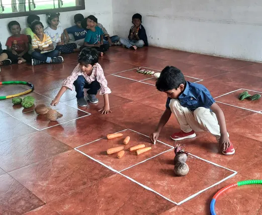 Ukg Bigger group activity 5_result Interactive counting exercise with various vegetables on the classroom floor at Vidhya Peetham i-School in Salem.
