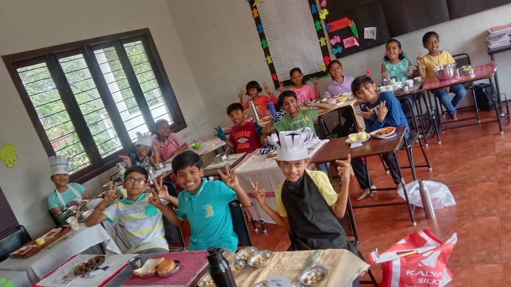 Young chefs in Grade 3 at Vidhya Peetham i-School wearing chef caps and aprons while preparing fruit salads and health snacks as part of their culinary skills development.
