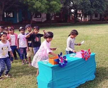Excited first graders participating in a Tamil words spelling game with colorful flashcards on a sunny day at one of the best schools in Salem.