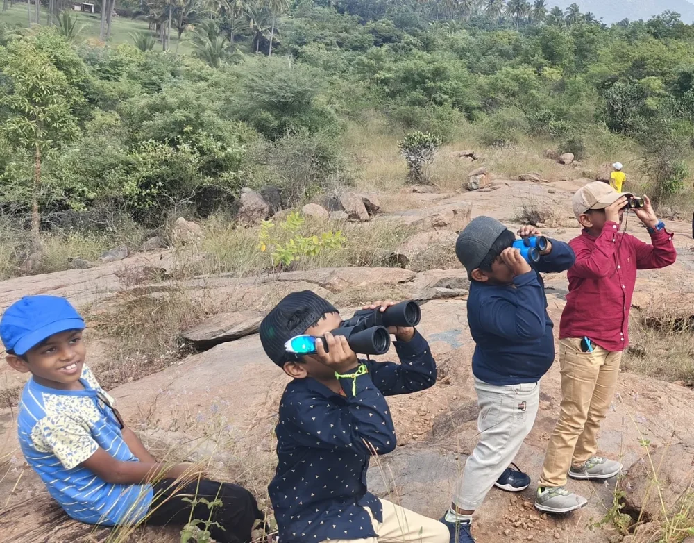 Eager students using binoculars to birdwatch during a school trip in Salem's natural surroundings.