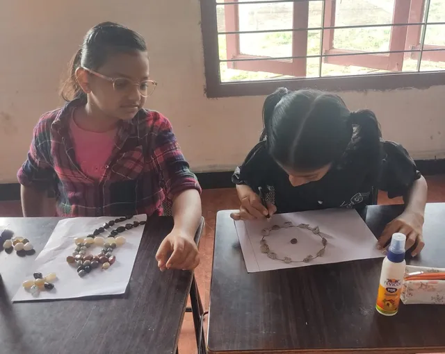 Creative hands at work in Vidhya Peetham i-School, gluing colorful pebbles to bring art projects to life.