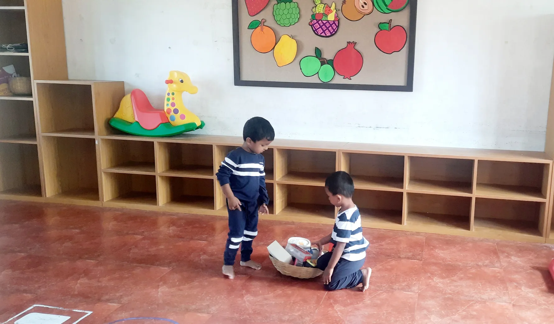 Two Pre-KG children excitedly picking objects from a basket during a shapes identification activity. ??