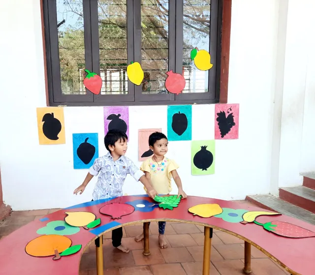 A child joyfully participating in a fruit shape matching game, identifying a banana among other fruit flashcards.