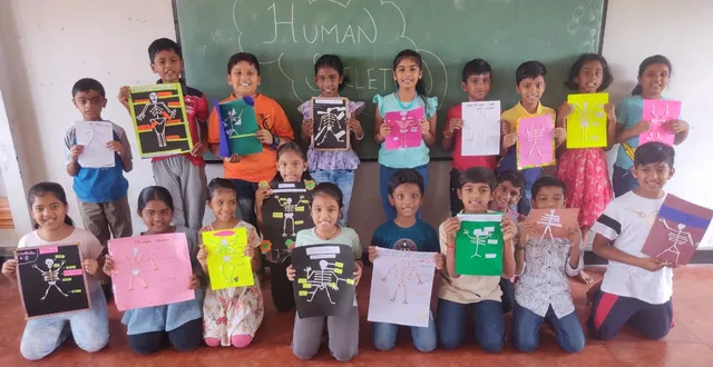 Enthusiastic children displaying their handmade skeleton charts after an educational activity in a school in Salem.