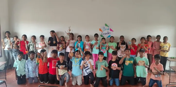 Vidhya Peetham i-School Grade 5 students displaying their handmade bird feeders in the classroom.
