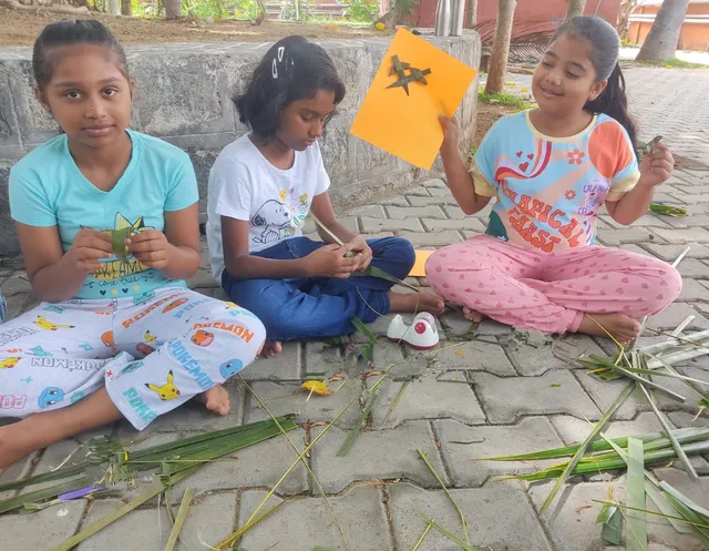 Students sitting outdoors and crafting with coconut leaves at Vidhya Peetham i-School.