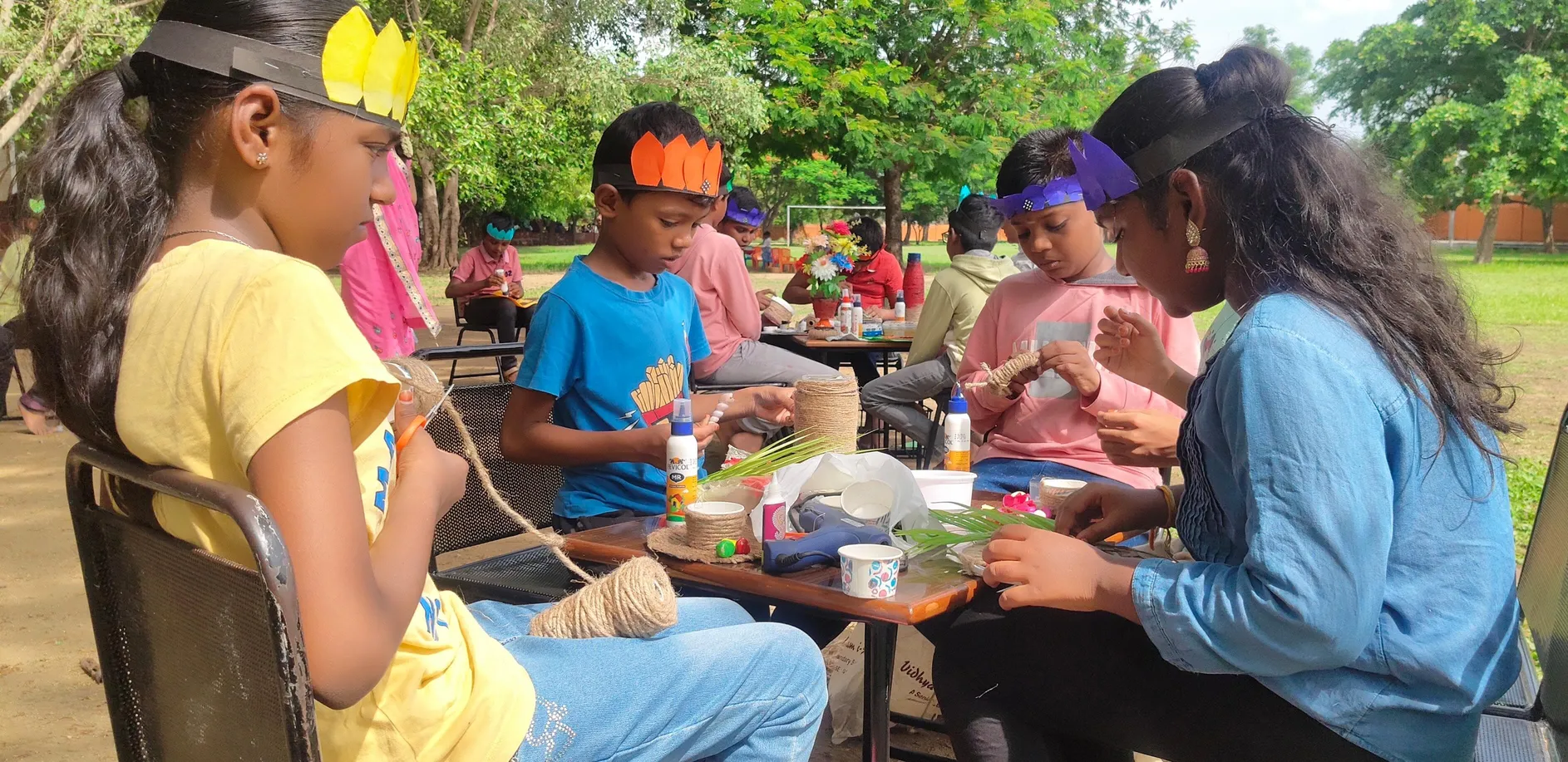 Children creating jute crafts outdoors.