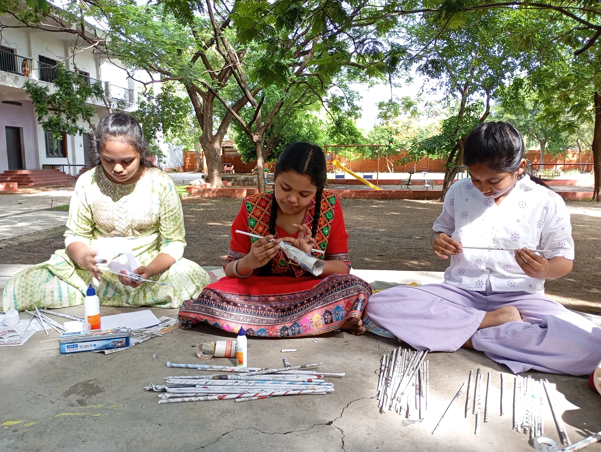 Girls creating various crafts with newspapers at Vidhya Peetham i-School.