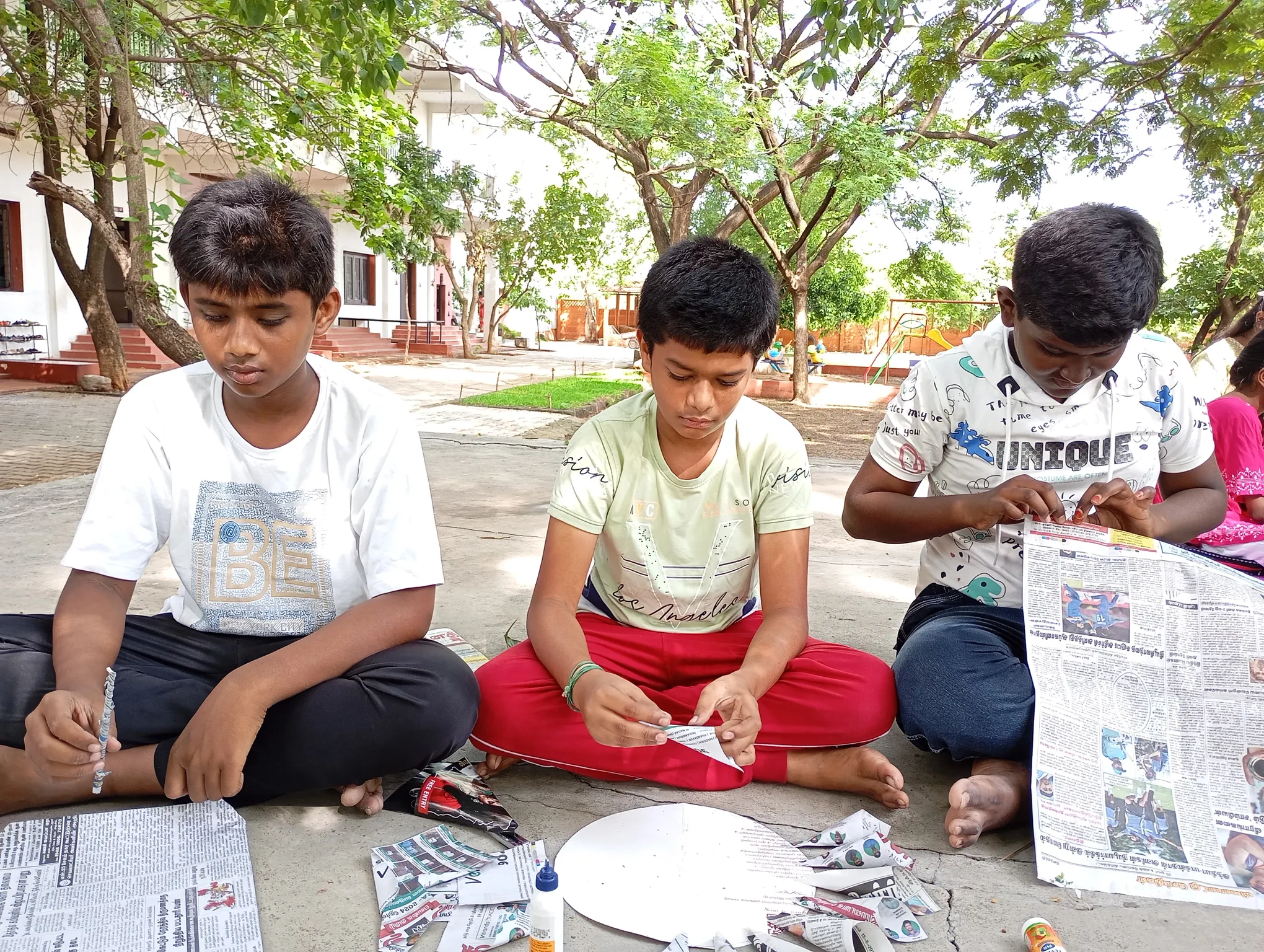 Students working on newspaper craft projects in a group activity.