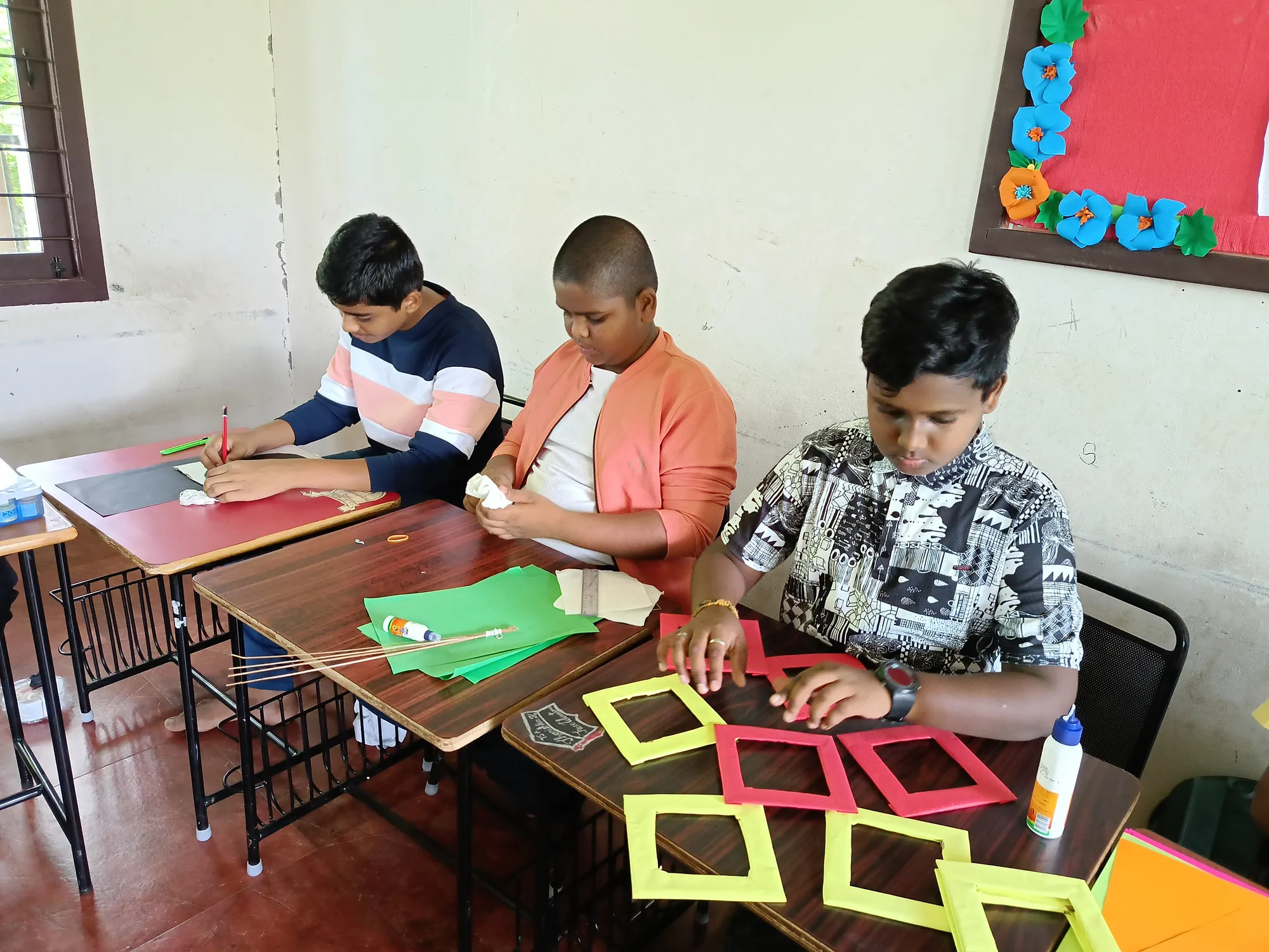 Group of boys making colorful wall hangings with cardboards and paints.