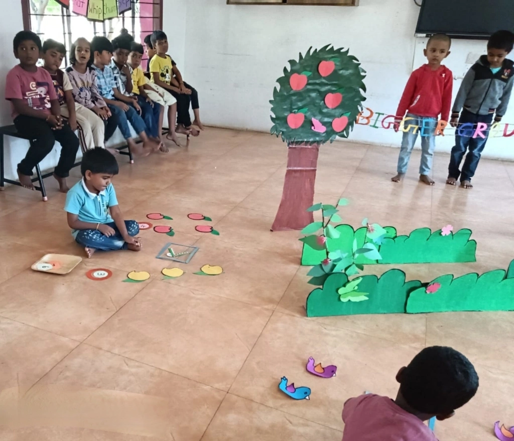 UKG students at Vidhya Peetham engaged in garden-themed bigger number sign activity with colorful props