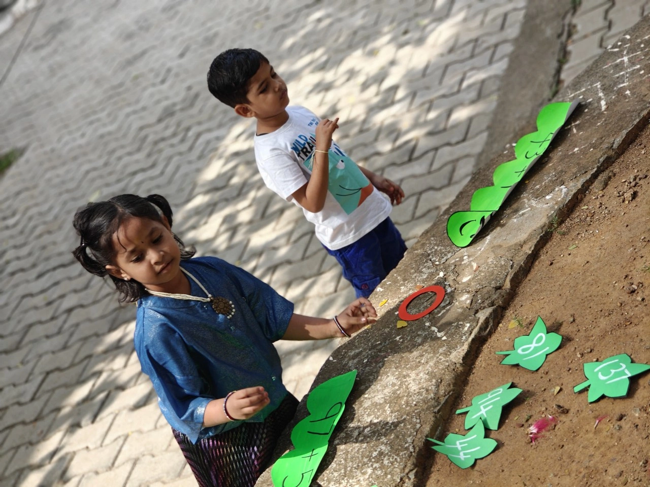 Children engaging in outdoor mathematics learning with leaf-shaped answer cards