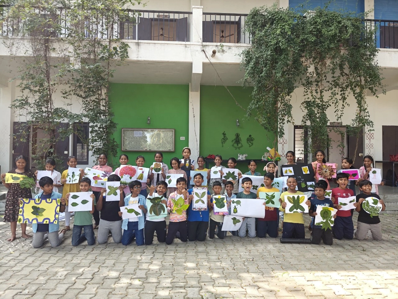 Students proudly displaying their leaf art creations in a group photo, showing diverse nature-inspired designs during their leaf art for kids activity
