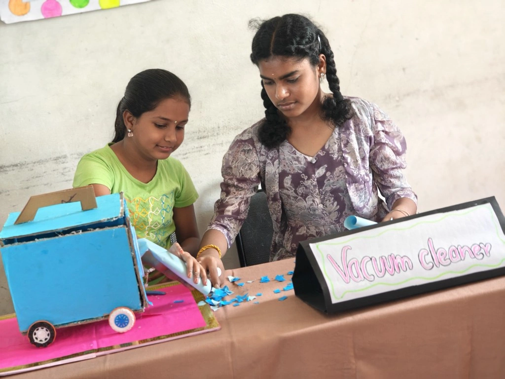 Two students working on their vacuum cleaner model with a clear project label display