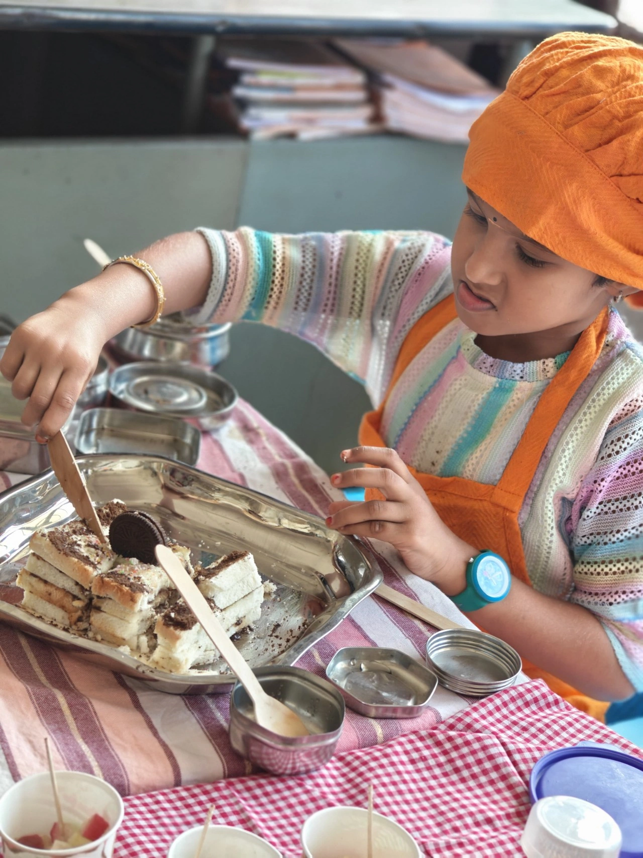 Student in orange chef's cap preparing a creative dessert with Oreo cookies at Vidhya Peetham i-School during flameless cooking activity