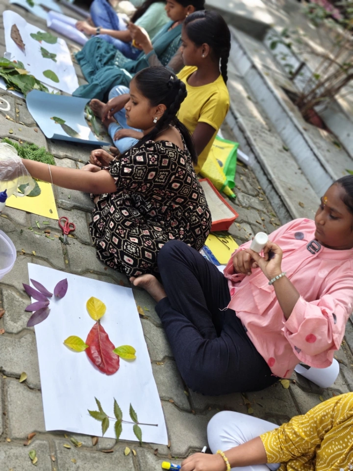 Two students working side by side on their leaf art projects, carefully arranging materials
