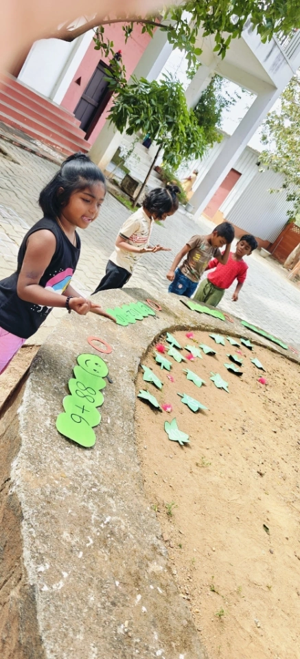 Young student solving horizontal addition problems on colorful caterpillar-shaped display board