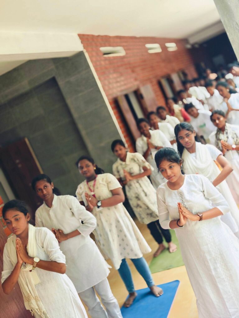 Older students stand in a line in a corridor with palms joined in front of the chest.