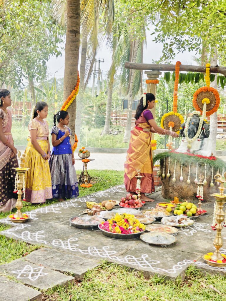A girl in a silk half-saree makes an offering at the Ganesha idol as three girls look on
