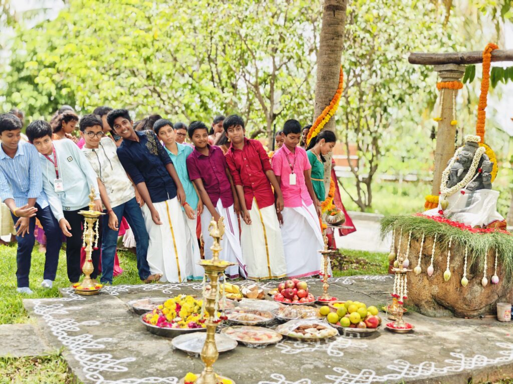 Older boys in shirts and veshtis stand in a line beside the shrine, brass lamps and offerings in front