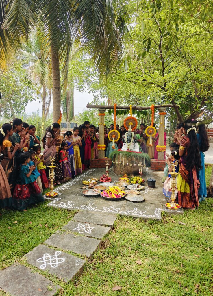 Students in traditional dress gather around the flower-decorated shrine with palms joined